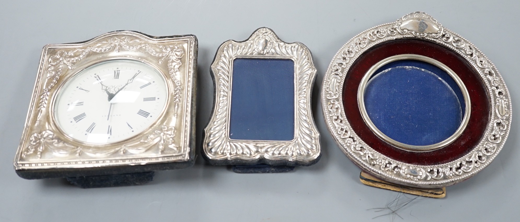 A modern silver mounted desk timepiece, 15.2cm and two mounted photograph frames, including Italian 925 and Edwardian repousse.